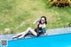 A woman in a black swimsuit sitting on the edge of a swimming pool.