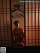 A woman in a red kimono sitting in front of a window.