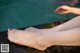 A woman's bare feet sitting on a wooden dock by the water.