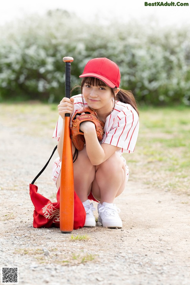 A woman in a baseball uniform crouching down with a bat.