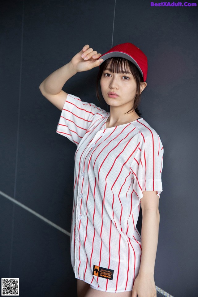 A woman wearing a baseball uniform and a red hat.
