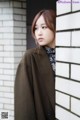 A woman leaning against a white brick wall.