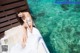 A woman in a white dress sitting on a bed in the water.