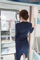 A woman in a blue dress is standing on a train.