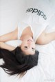 A woman laying on top of a bed wearing a white shirt.