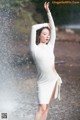 A woman in a white dress standing in the rain.