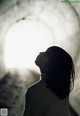 A woman standing in a tunnel looking up at the sky.