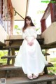 A woman in a white dress sitting on a wooden staircase.