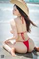 A woman in a red bikini sitting on the beach.