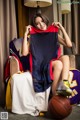 A woman sitting on a chair holding a basketball jersey.