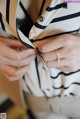 A woman is putting on a black and white striped shirt.