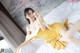 A woman in a yellow dress laying on a bed.