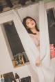 A woman standing in a bathroom next to a shower curtain.