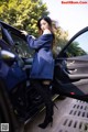 A woman standing next to a car with the door open.