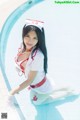 A woman dressed as a nurse sitting on the edge of a pool.