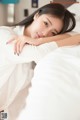 A woman laying on a bed with her arms crossed.