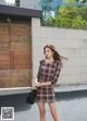 A woman in a plaid dress is walking down the street.