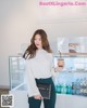 A woman standing in front of a display case holding a drink.