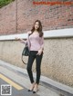 A woman standing in front of a brick wall.