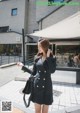 A woman in a black dress is walking down the street.