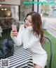 A woman sitting at a table looking at her phone.