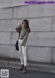 A woman standing in front of a concrete wall.