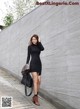 A woman in a black dress is walking down the street.