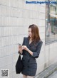 A woman in a black and white striped blazer is looking at her phone.