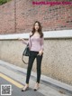 A woman standing in front of a brick wall.