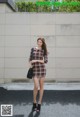 A woman in a plaid dress is standing on the street.