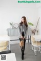 A woman standing in front of a white table and chairs.