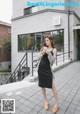 A woman in a black dress is holding a cup of coffee.