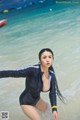 A woman in a wet suit standing in the ocean.