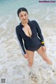 A woman in a black swimsuit standing in the ocean.