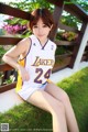 A woman in a Lakers uniform sitting on a bench.