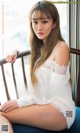 A woman sitting on a chair in a white dress.