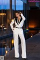 A woman in a white suit standing next to a pool.