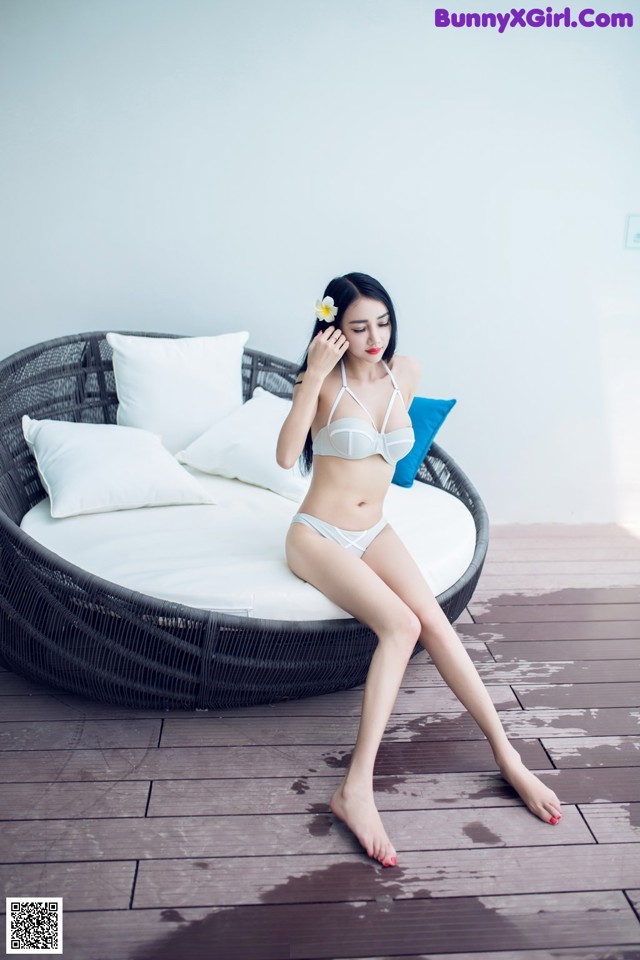 A woman in a white bikini sitting on a couch.