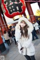 A woman in a white coat talking on a cell phone.