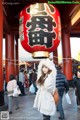 A woman standing in front of a large red lantern.