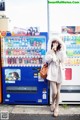 A woman standing in front of a vending machine.