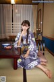 A woman in a kimono sitting on the floor in a room.